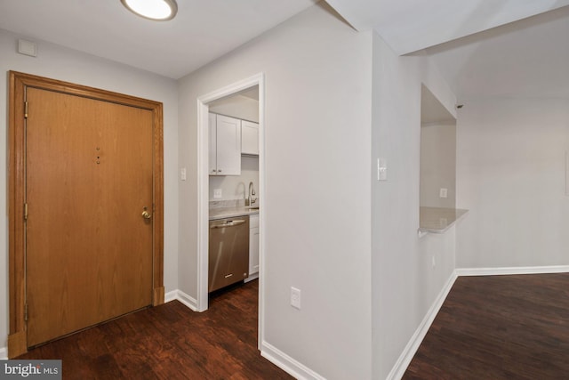 hallway featuring a sink, baseboards, and dark wood-style flooring