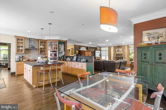 dining area with dark wood-type flooring, recessed lighting, a large fireplace, and ornamental molding