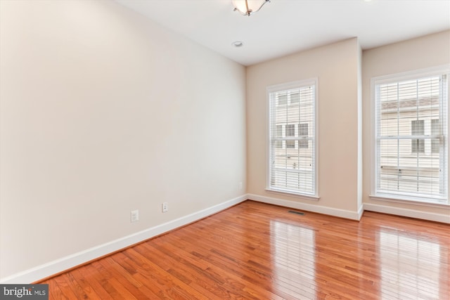 spare room with light wood-style flooring, visible vents, and baseboards