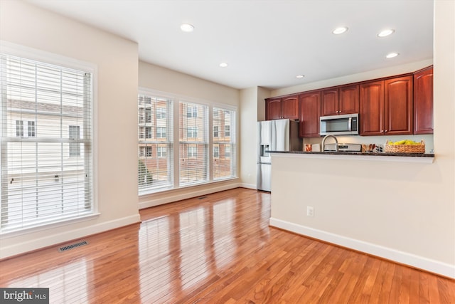 kitchen featuring light wood-type flooring, visible vents, dark countertops, stainless steel appliances, and a peninsula