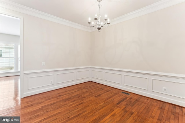 spare room featuring visible vents, crown molding, an inviting chandelier, and hardwood / wood-style floors