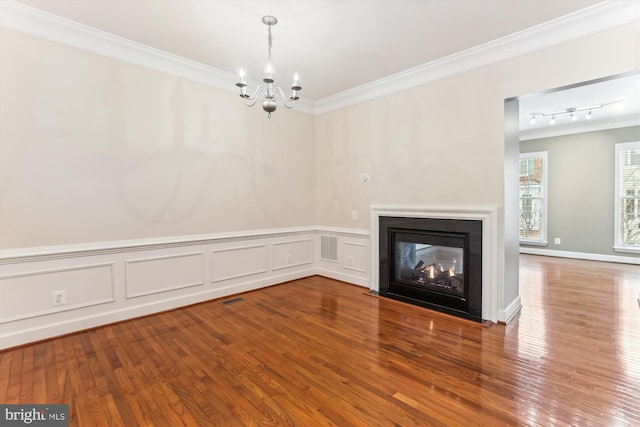 unfurnished living room featuring visible vents, a notable chandelier, ornamental molding, hardwood / wood-style flooring, and a multi sided fireplace