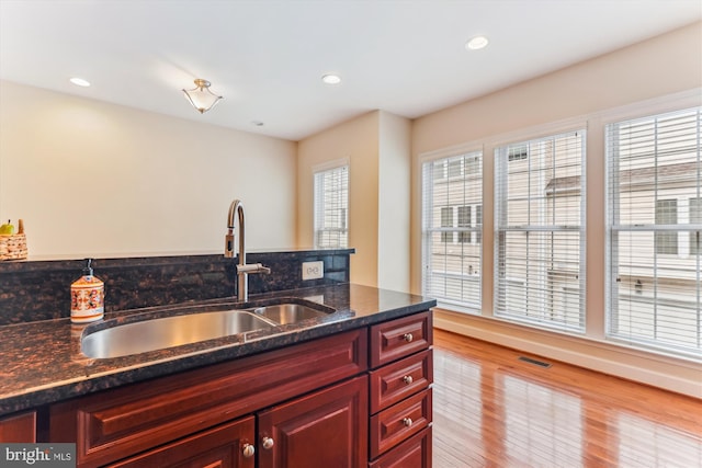 kitchen featuring visible vents, a sink, recessed lighting, wood finished floors, and reddish brown cabinets