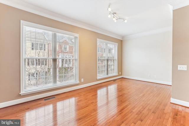 spare room with visible vents, track lighting, light wood-style floors, crown molding, and baseboards