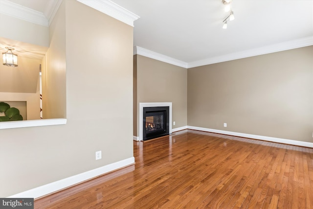 unfurnished living room featuring wood finished floors, baseboards, a fireplace with flush hearth, ornamental molding, and track lighting