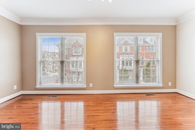 spare room featuring baseboards, a healthy amount of sunlight, and hardwood / wood-style floors