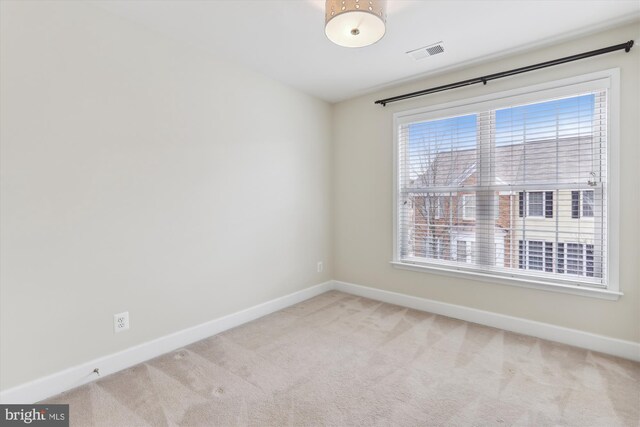 carpeted spare room with visible vents and baseboards