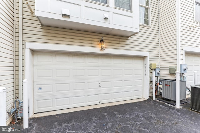 garage featuring aphalt driveway and cooling unit