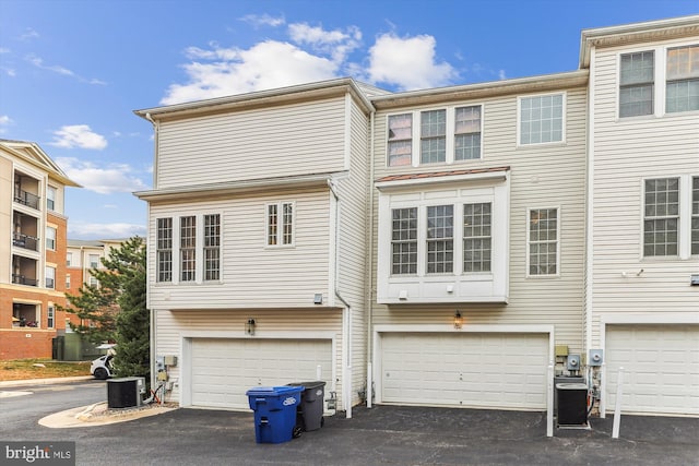 rear view of house featuring a garage, driveway, and central AC