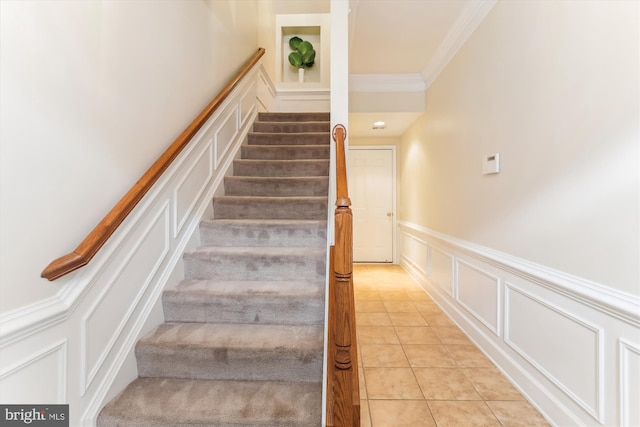 stairway featuring a decorative wall, wainscoting, crown molding, and tile patterned flooring