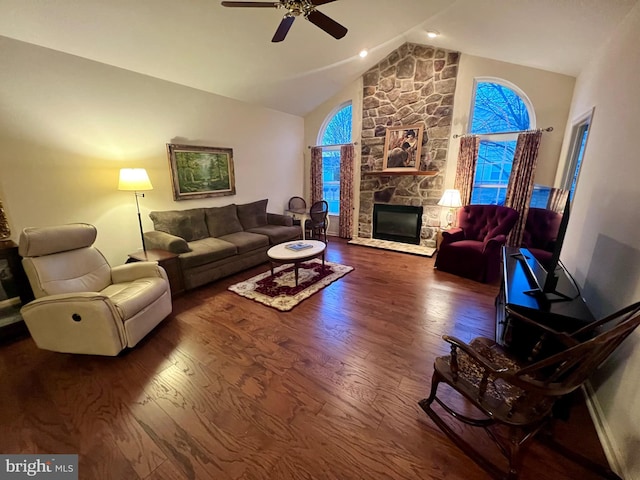 living room featuring baseboards, ceiling fan, dark wood-type flooring, a fireplace, and high vaulted ceiling