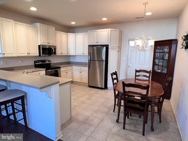 kitchen with stainless steel appliances, hanging light fixtures, a peninsula, and white cabinets