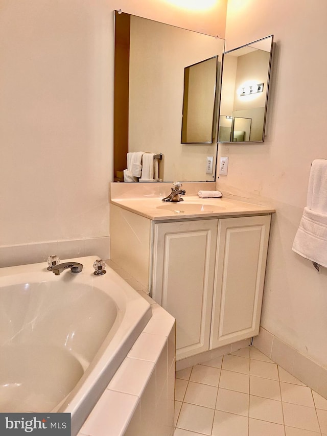 full bath with tiled tub, vanity, and tile patterned floors