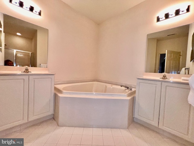 full bath with a garden tub, a shower stall, two vanities, and tile patterned floors