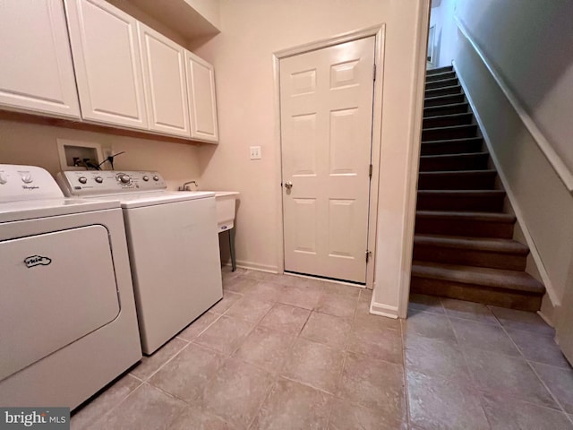 clothes washing area with baseboards, cabinet space, and washing machine and clothes dryer