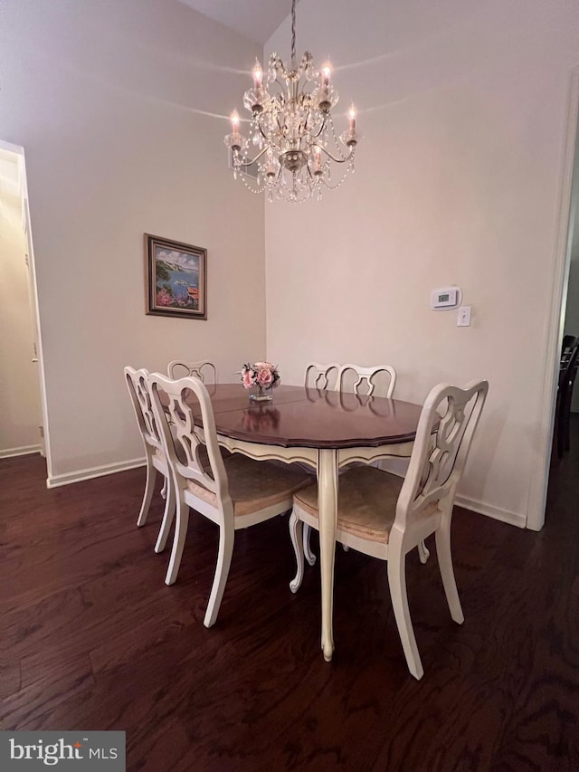 dining room featuring dark wood-type flooring, a chandelier, and baseboards