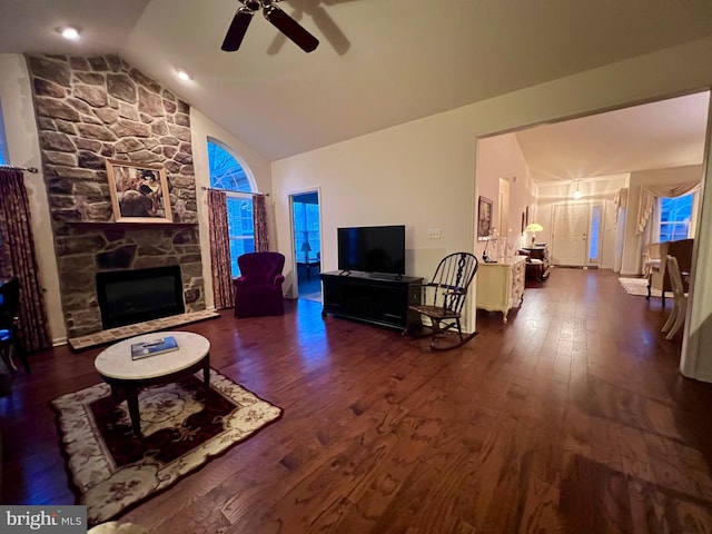 living area with high vaulted ceiling, a fireplace, dark wood finished floors, and ceiling fan