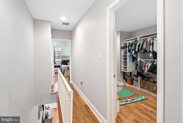 corridor with visible vents, baseboards, and wood finished floors