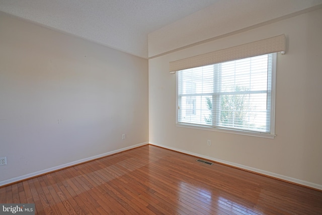 spare room featuring baseboards, visible vents, and hardwood / wood-style floors