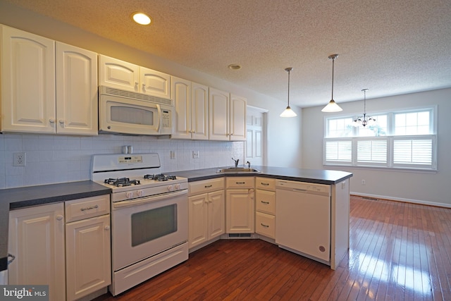 kitchen featuring white appliances, dark wood finished floors, dark countertops, a peninsula, and white cabinetry