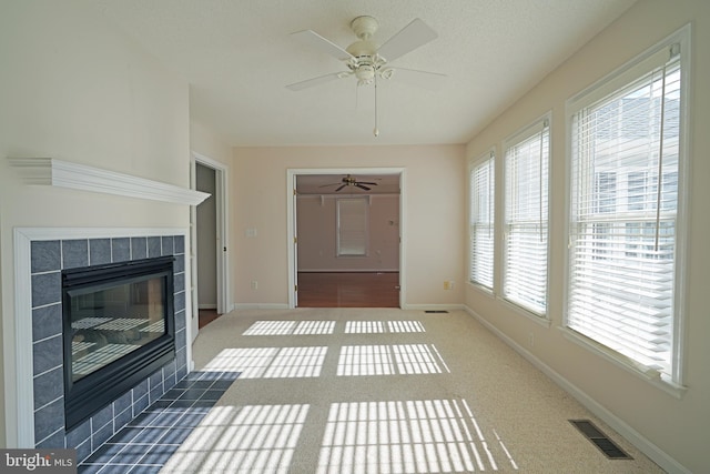 unfurnished living room featuring baseboards, visible vents, carpet flooring, and a tile fireplace