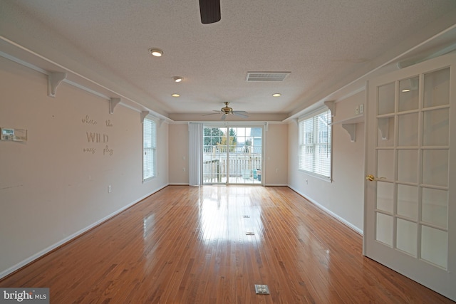 unfurnished room with visible vents, a ceiling fan, a textured ceiling, wood finished floors, and baseboards