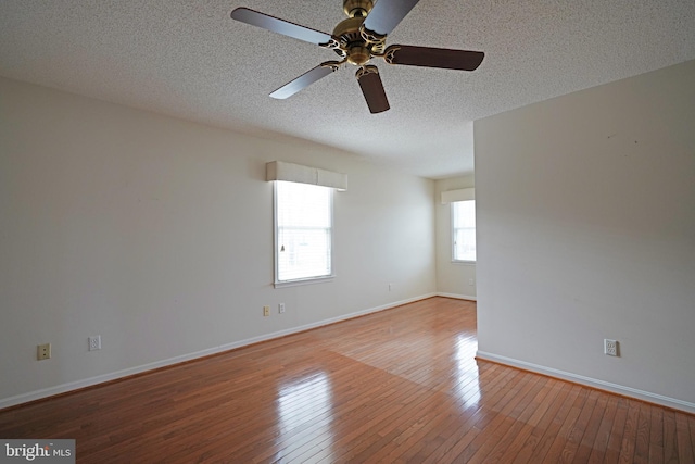 unfurnished room featuring wood-type flooring, baseboards, and a textured ceiling