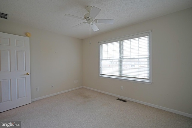 carpeted empty room with a textured ceiling, visible vents, and baseboards