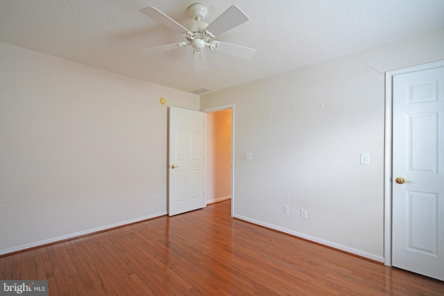 spare room with a ceiling fan, wood-type flooring, baseboards, and a textured ceiling