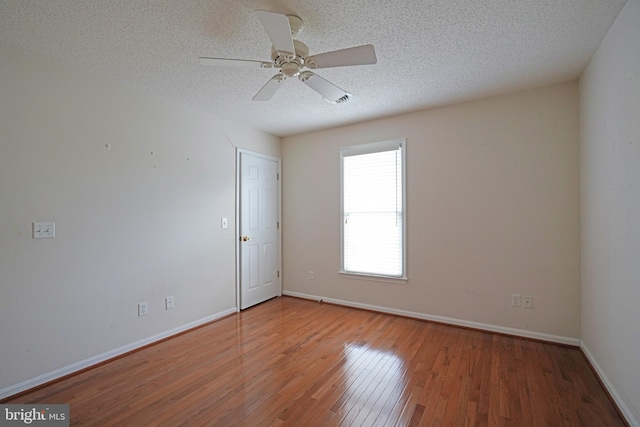 unfurnished room featuring wood-type flooring, ceiling fan, a textured ceiling, and baseboards