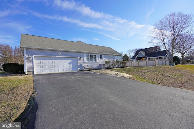 single story home featuring a garage, driveway, central AC unit, and fence