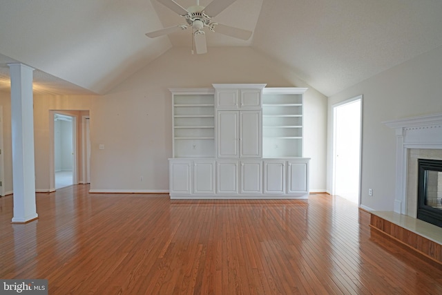 unfurnished living room with a fireplace, decorative columns, light wood-style floors, a ceiling fan, and vaulted ceiling