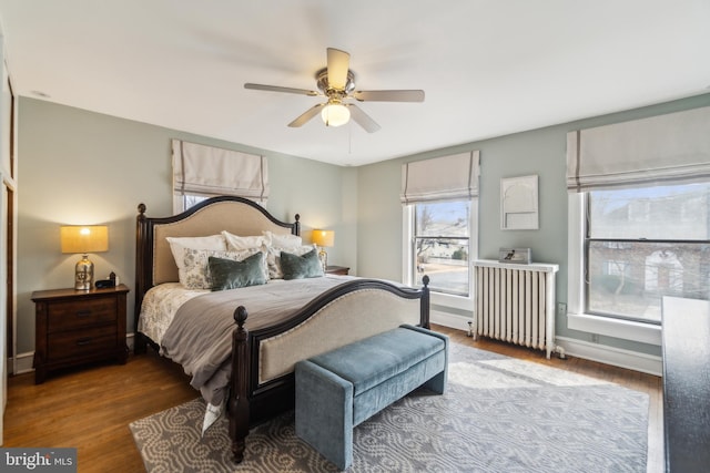 bedroom with radiator, a ceiling fan, baseboards, and wood finished floors