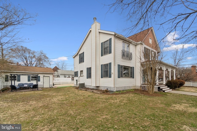 view of side of property with a chimney, a lawn, fence, and cooling unit