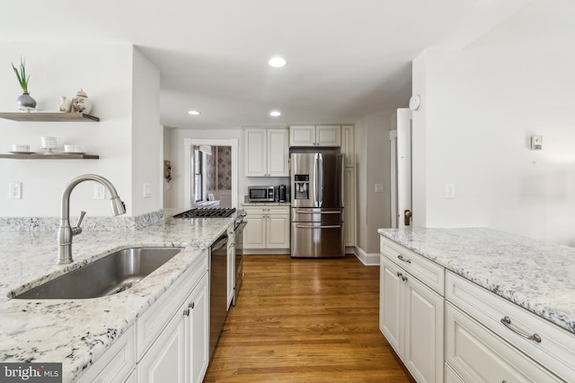 kitchen with recessed lighting, stainless steel appliances, wood finished floors, a sink, and white cabinetry