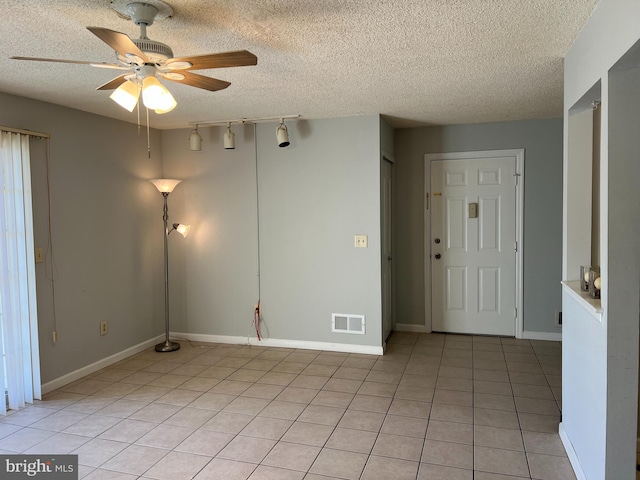 spare room with light tile patterned floors, a textured ceiling, visible vents, and a ceiling fan