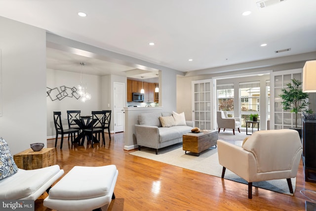 living area with recessed lighting, visible vents, a notable chandelier, and light wood-style flooring