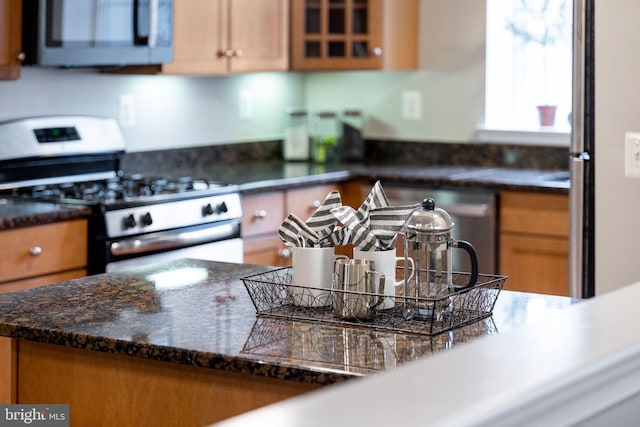 kitchen with brown cabinets, glass insert cabinets, and stainless steel appliances