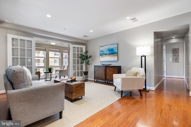 living room with light wood finished floors, recessed lighting, visible vents, and baseboards