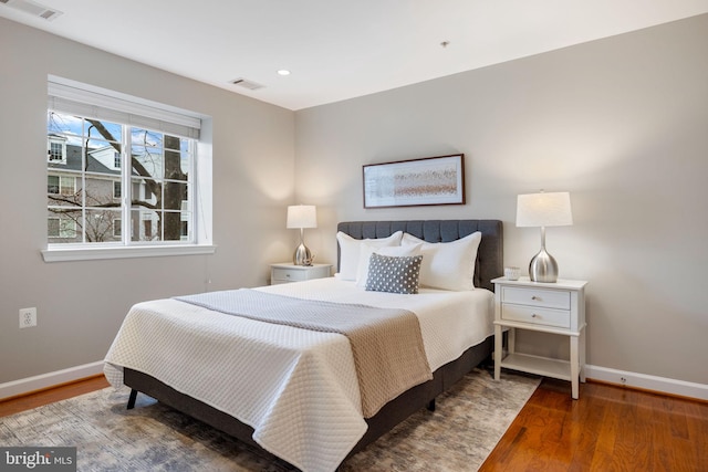 bedroom featuring baseboards, visible vents, and wood finished floors