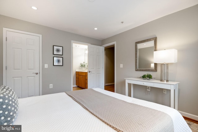 bedroom with recessed lighting, ensuite bathroom, baseboards, and wood finished floors