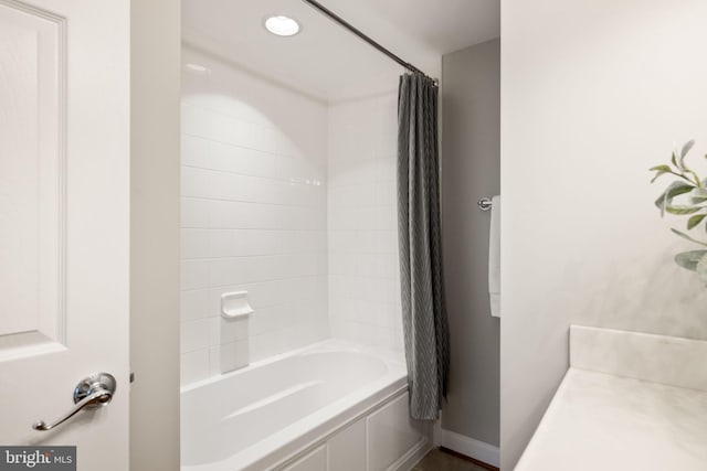 bathroom featuring shower / bath combo and baseboards