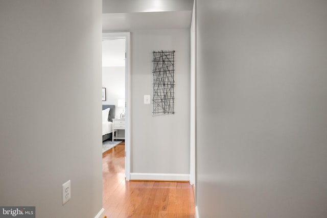 hallway featuring light wood-style flooring and baseboards