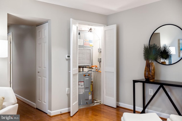 bedroom featuring baseboards, wood finished floors, and electric water heater