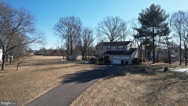 view of side of home featuring an attached garage, a shed, aphalt driveway, and a yard