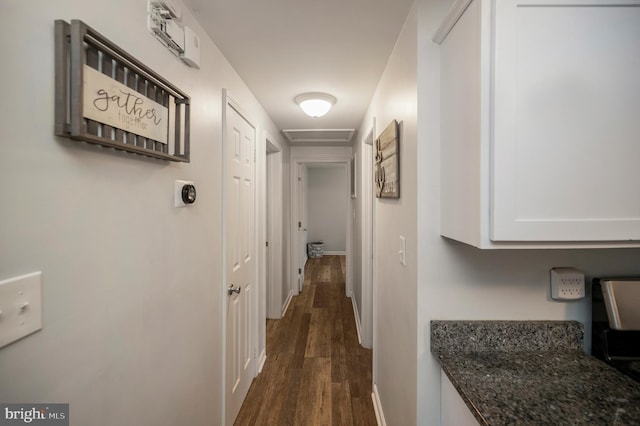 corridor featuring baseboards and dark wood finished floors