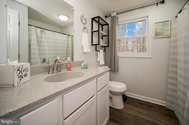 bathroom featuring toilet, vanity, wood finished floors, baseboards, and visible vents