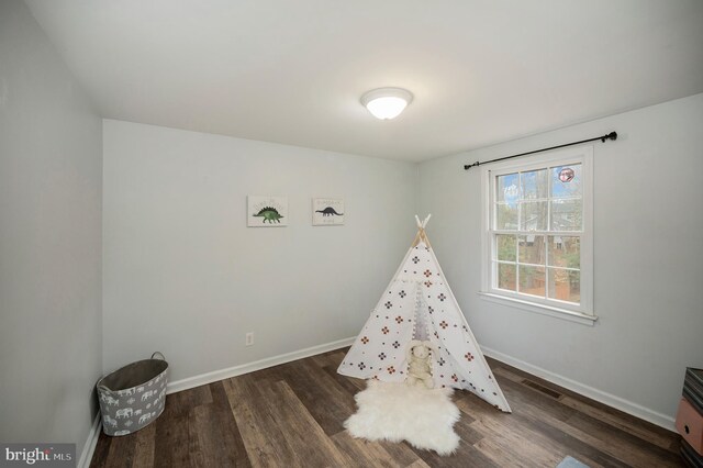 recreation room featuring baseboards, visible vents, and wood finished floors