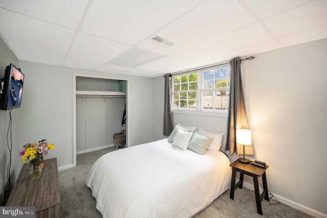 carpeted bedroom featuring visible vents, baseboards, a closet, and a paneled ceiling