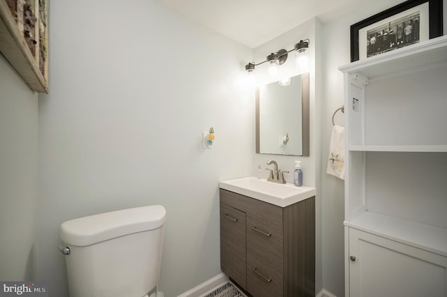 half bath featuring baseboards, toilet, and vanity